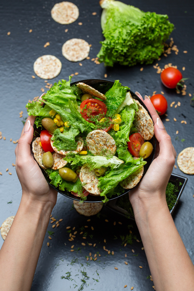 vertical-closeup-person-holding-bowl-salad-with-crackers-vegetables-lights Vegan lifestyle